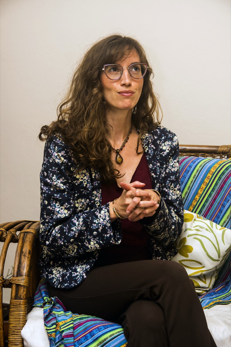 Marcela escutando, sentada na poltrona do consultório